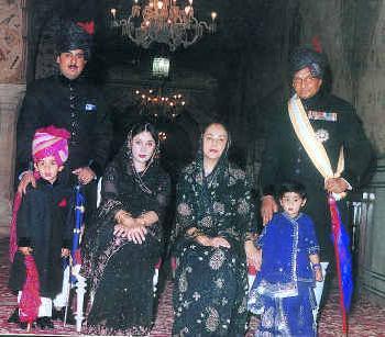 This is the current royal family of Jaipur. Standing on the right with a white sash is His Highness Brigadier Maharaja Sawai Bhawani Singh. In front of the Maharaja in the blue dress is his granddaughter. Seated next to her is Her Highness Maharani Padmini Devi. The Princess Diya Kumari is seated next to the Maharani, and standing on the left is the princess's husband Mr. Narendra Singh. Finally the heir to the Jaipur Gaddi, Maharaj Kumar Padmanabh Singh is standing in the prink turban. He is the son of Princess Diya Kumari and Mr. Narendra Singh, and was recently adopted by Maharaja Bhawani Singh accompanied by a stately ceremony as the heir to the Jaipur Gaddi.